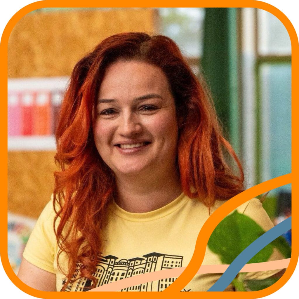 Portret van Lindsay. Een witte vrouw met lang donker haar, waarvan het onderste deel rood geverfd is. Ze lacht vriendelijk en draagt een geel T-shirt.